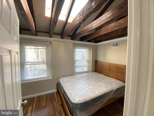 bedroom with beamed ceiling, dark hardwood / wood-style flooring, and multiple windows