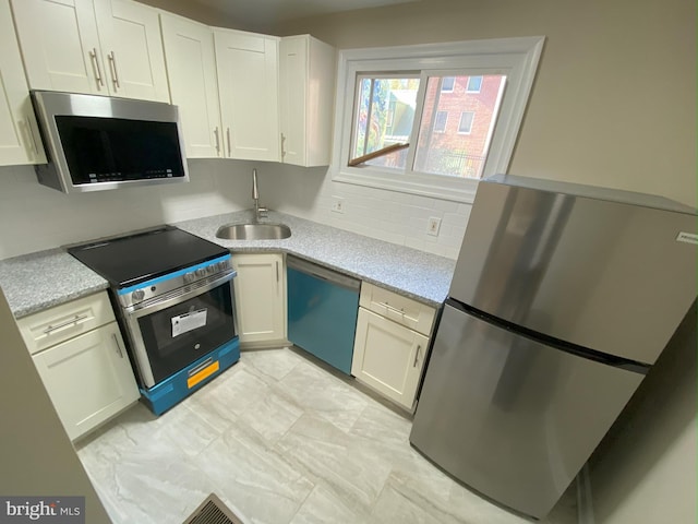 kitchen with appliances with stainless steel finishes, sink, and white cabinetry