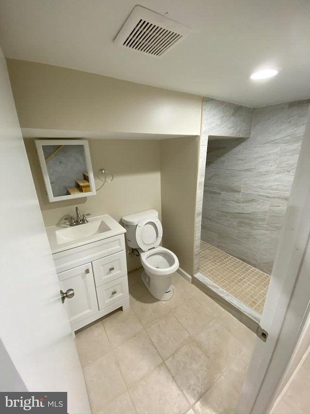 bathroom featuring toilet, vanity, tile patterned flooring, and tiled shower