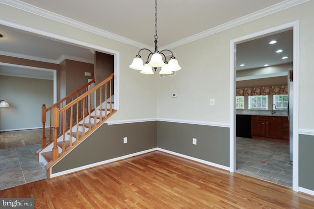 unfurnished dining area featuring crown molding, wood-type flooring, sink, and an inviting chandelier