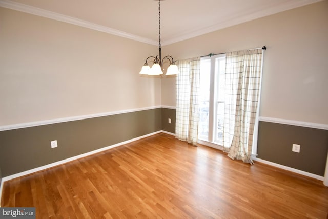 empty room featuring a notable chandelier, a healthy amount of sunlight, crown molding, and hardwood / wood-style floors