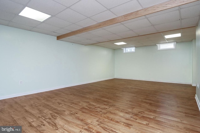 basement featuring light wood-type flooring and a drop ceiling