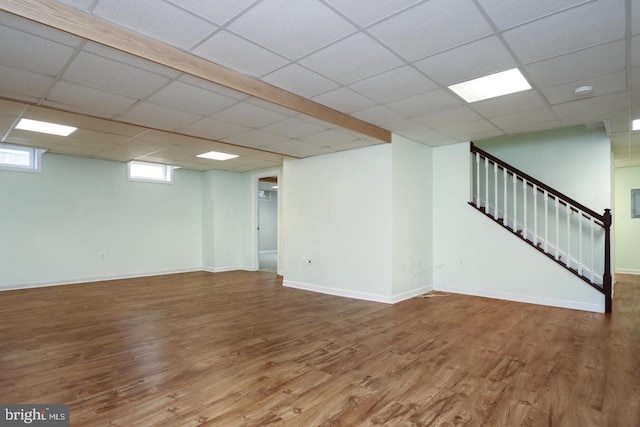 basement with hardwood / wood-style flooring and a paneled ceiling