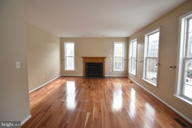 unfurnished living room featuring a wealth of natural light and light wood-type flooring