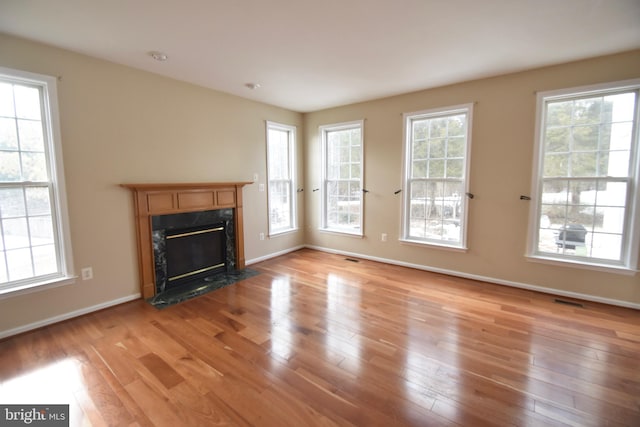 unfurnished living room with light wood-type flooring and a high end fireplace