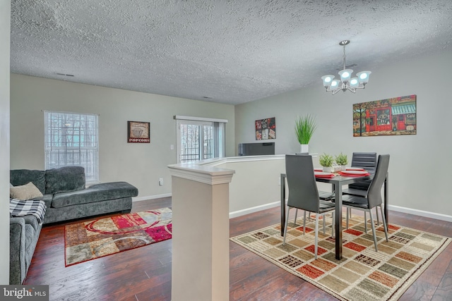 dining room featuring a textured ceiling, a notable chandelier, and dark hardwood / wood-style flooring