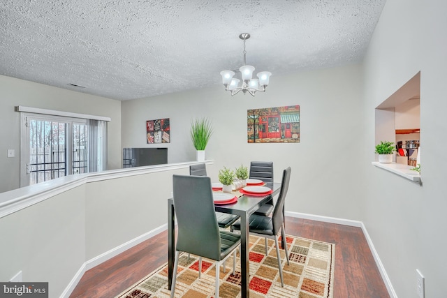 dining space featuring hardwood / wood-style floors, a textured ceiling, and a notable chandelier