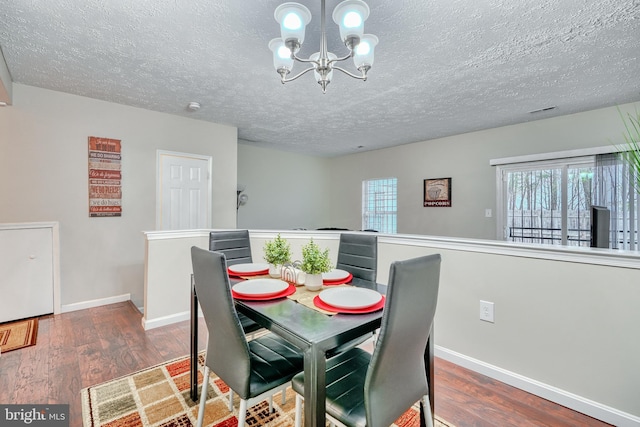 dining room with dark wood-type flooring, an inviting chandelier, and a textured ceiling