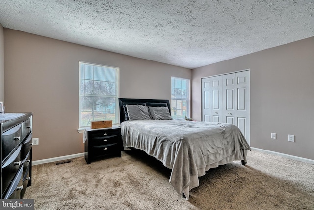 bedroom featuring light carpet, a textured ceiling, and a closet