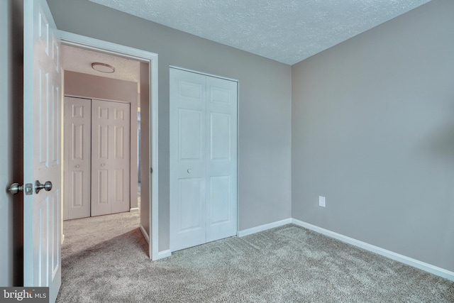 unfurnished bedroom featuring a closet, a textured ceiling, and carpet