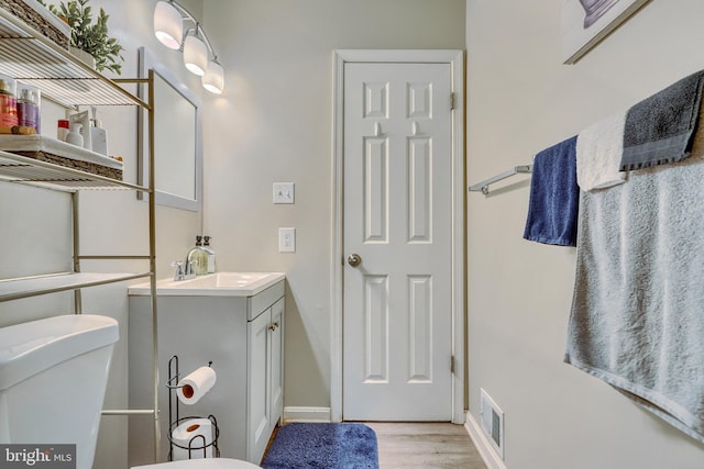 bathroom with vanity, toilet, and wood-type flooring