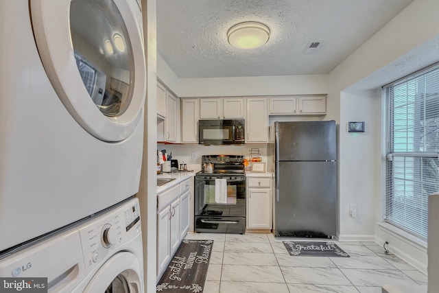 kitchen featuring stacked washer / drying machine, a textured ceiling, and black appliances