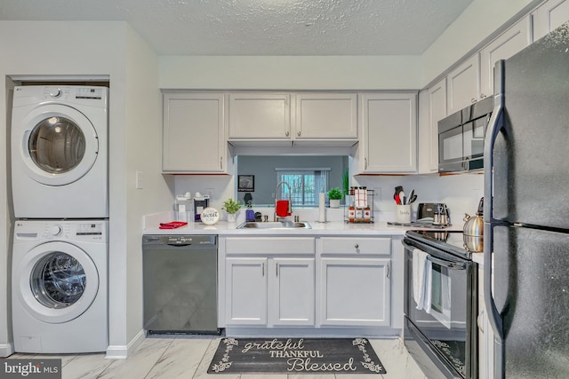 kitchen with stacked washer / dryer, sink, a textured ceiling, and black appliances