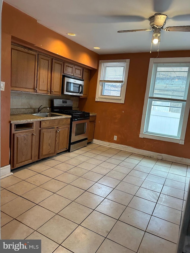 kitchen with appliances with stainless steel finishes, sink, light tile patterned floors, and plenty of natural light