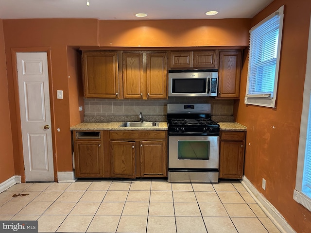 kitchen featuring sink, appliances with stainless steel finishes, backsplash, light stone counters, and light tile patterned flooring