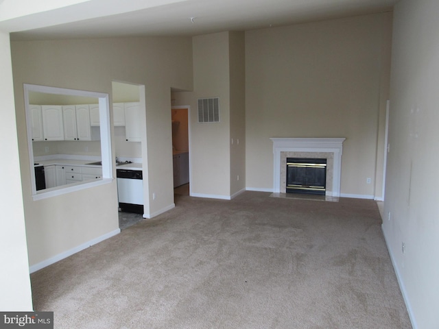 unfurnished living room featuring lofted ceiling, a high end fireplace, and light carpet