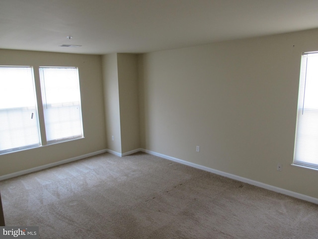 spare room featuring light colored carpet and a healthy amount of sunlight