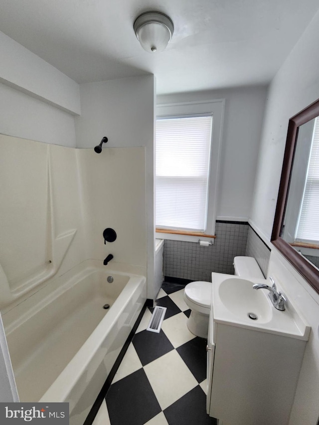 full bathroom featuring tile walls, toilet, vanity, and bathing tub / shower combination