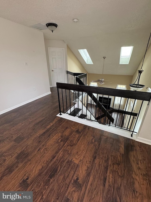 stairs featuring hardwood / wood-style flooring, ceiling fan, lofted ceiling with skylight, and a textured ceiling