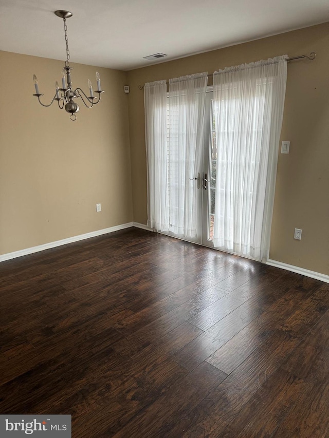 unfurnished room featuring a notable chandelier and dark hardwood / wood-style floors