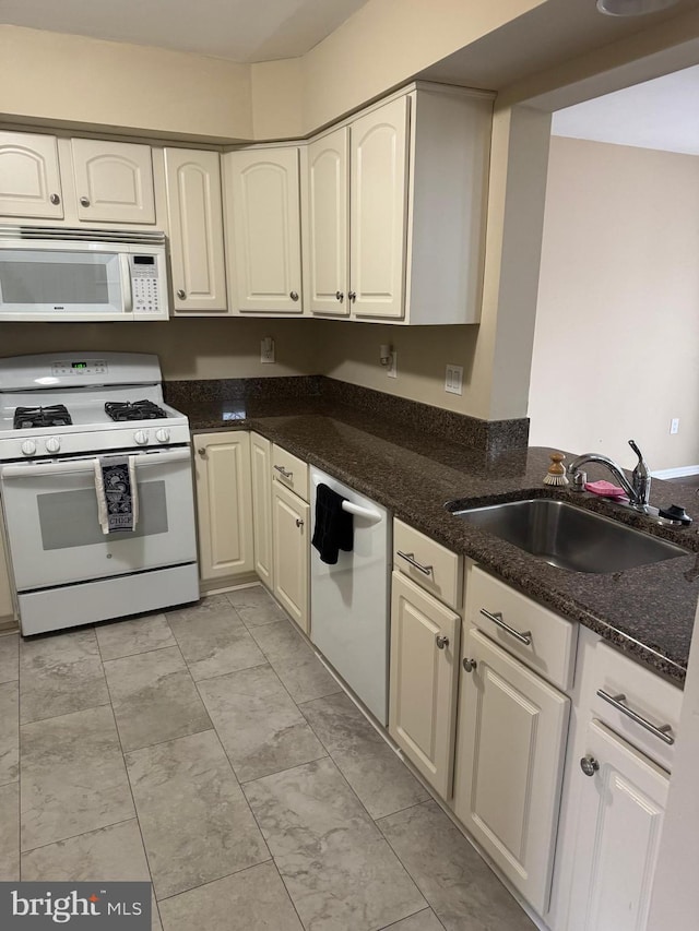 kitchen with sink, dark stone countertops, and white appliances