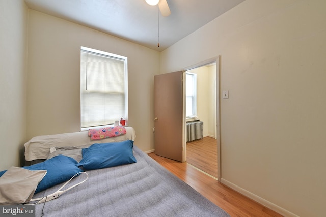 bedroom featuring light wood-type flooring, ceiling fan, and radiator heating unit