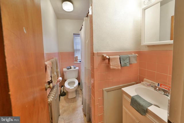 bathroom with tile walls, toilet, radiator, and vanity