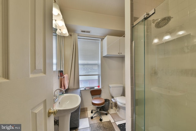 bathroom with a shower with shower door, sink, tile patterned floors, and toilet