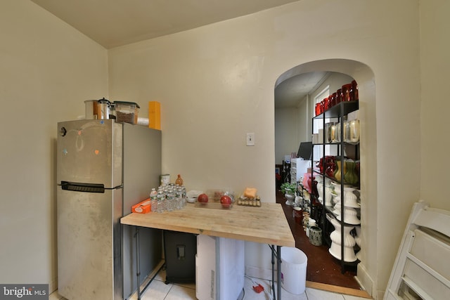 kitchen with light tile patterned floors, stainless steel fridge, and wooden counters