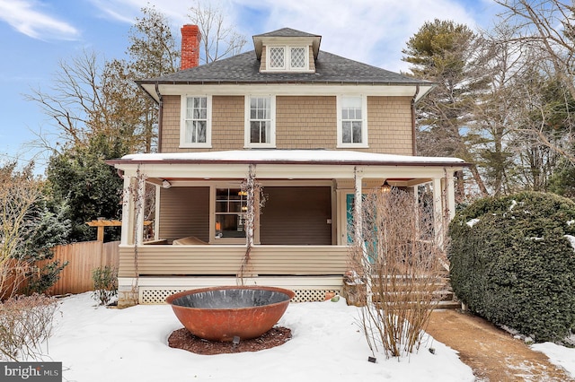 american foursquare style home featuring a porch and fence