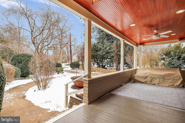 snow covered deck with ceiling fan and a porch