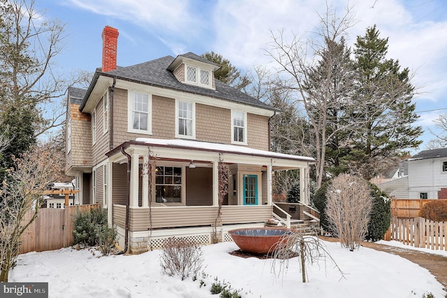 traditional style home featuring a chimney, fence, and a porch