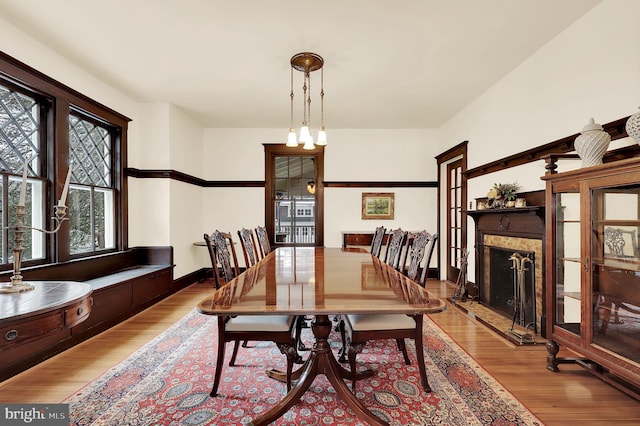 dining space featuring baseboards, a fireplace with raised hearth, and wood finished floors