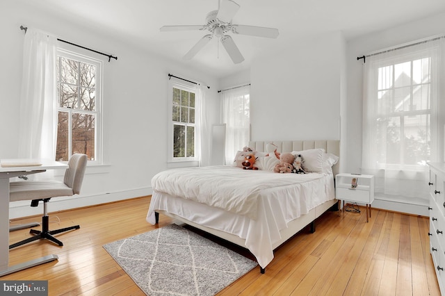 bedroom with a ceiling fan, baseboards, and light wood finished floors