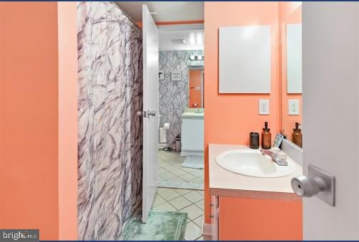 bathroom with vanity, curtained shower, tile patterned floors, and tile walls