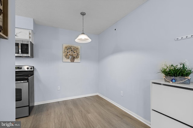 kitchen featuring decorative light fixtures, a textured ceiling, light hardwood / wood-style flooring, appliances with stainless steel finishes, and white cabinets