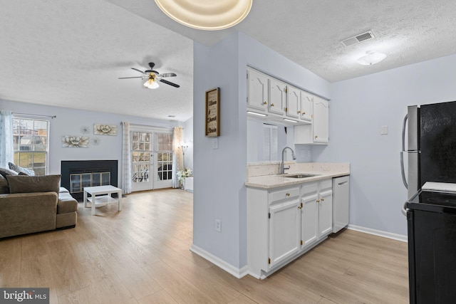 kitchen with stainless steel appliances, sink, white cabinets, and light hardwood / wood-style flooring