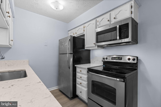 kitchen with sink, white cabinetry, a textured ceiling, appliances with stainless steel finishes, and dark hardwood / wood-style flooring