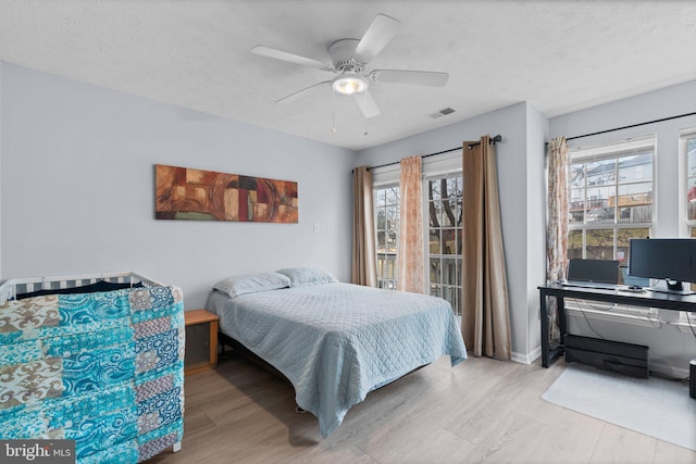 bedroom with multiple windows, light hardwood / wood-style floors, and a textured ceiling