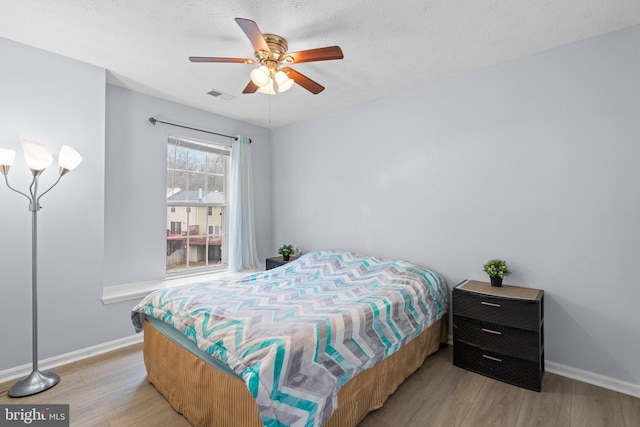 bedroom featuring a textured ceiling, ceiling fan, and light hardwood / wood-style flooring