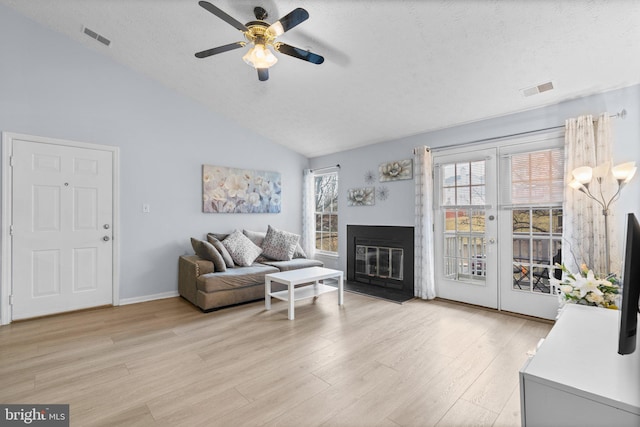 living room with lofted ceiling, a textured ceiling, light hardwood / wood-style flooring, and ceiling fan