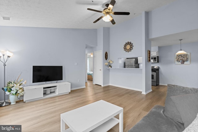 living room with ceiling fan, high vaulted ceiling, hardwood / wood-style floors, and a textured ceiling