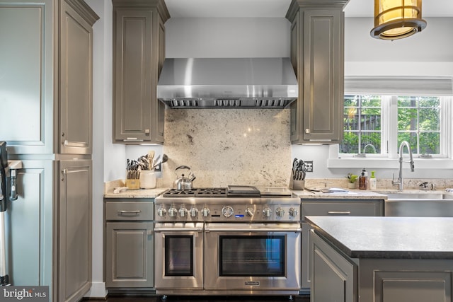 kitchen featuring decorative backsplash, sink, range with two ovens, and wall chimney range hood