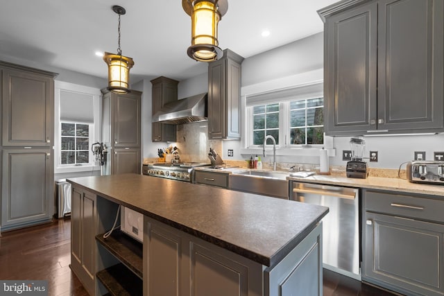 kitchen with dishwasher, wall chimney range hood, a center island, sink, and dark hardwood / wood-style flooring