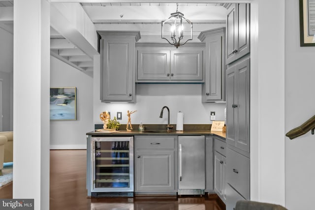 bar with gray cabinets, dark hardwood / wood-style floors, fridge, beverage cooler, and sink