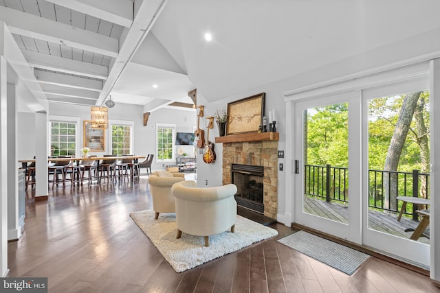 living room with wood ceiling, dark hardwood / wood-style floors, a stone fireplace, and vaulted ceiling with beams