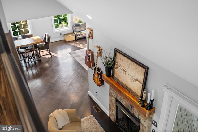 living room featuring vaulted ceiling, a fireplace, and dark hardwood / wood-style floors