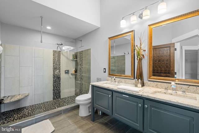 bathroom featuring vanity, toilet, and tiled shower