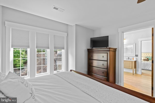 bedroom with ceiling fan, sink, ensuite bathroom, and hardwood / wood-style flooring