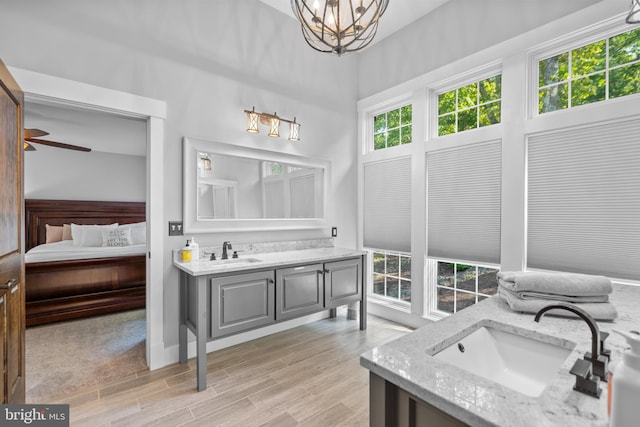 bathroom with vanity, a wealth of natural light, ceiling fan with notable chandelier, and hardwood / wood-style floors